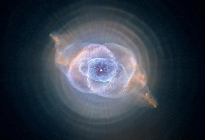 Photo of the 'Cat's eye nebula' courtesy of NASA. A point of light seems to explode with baloons of blue and orange gas.